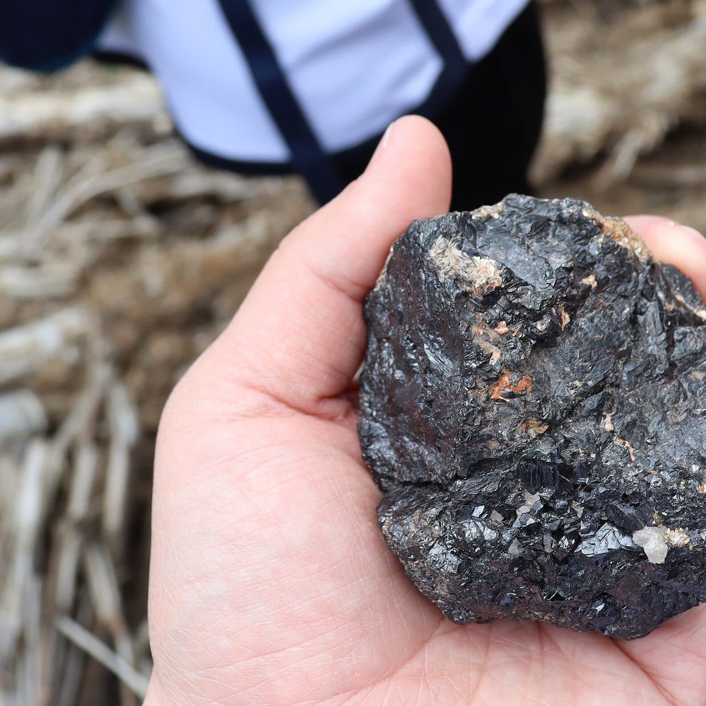 Raw coltan ore held in hand for scale
